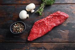 Whole tri tip steak with fresh seasoningsm thyme, organic tri-tip roast with fat marbled through the meat ready to roast or barbecue on rustic wooden background, top view