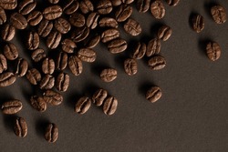 Roasted coffee beans background. Many aromatic coffee beans on a dark background. View from above. The concept of an advertising banner for a coffee shop or chain of commodity production.
