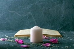 Magic still life with pink candle and old herbalist book. Esoteric and pagan rituals, witchcraft Wiccan or spiritual practice (healing). Ritual for love. Herbal treatment