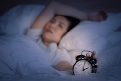 Insomnia in middle-aged women. An Asian woman tries to sleep but she cannot sleep because she has anxiety and stress from work. This symptom should be seen by a doctor for treatment.