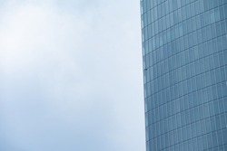 Close up of the facade of a modern tall skyscraper, with steel and glass facade, on the left. Dark overcasted sky on the right. Citylife district, Milan, Italy.