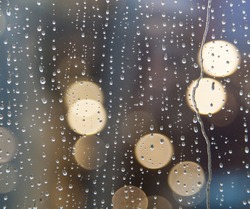 Drops of rain on window with abstract lights