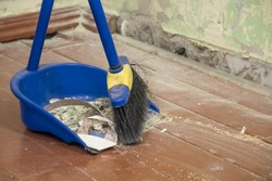 Clean up after repairs. Sweep up construction debris with a brush in a dustpan. Sweeping at home. Tools for cleaning the house. Make home repairs. The dust and debris after the renovation.