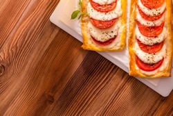 Two rectangular mini pizzas with tomatoes and mozzarella on a wooden table top view.