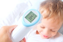 A non-contact digital infrared thermometer recorded the normal body temperature of a child.The boy is recovering from an illness.Successful prevention of colds and flu in children concept. 