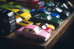front view assorted metal colorful toy car collection sitting on the edge of a table with a pink one in the front selective focus natural light