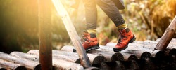 Woman hiking in the mountain. View of hiking boots on wooden bridge in the forest.