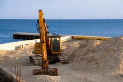 Excavator at sea straightens the sand for the beach.