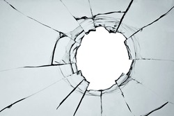Broken window, background of cracked glass with a hole from a shot or smash. Abstract cracked texture with white background in the middle