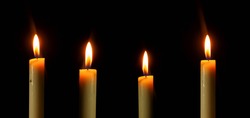 Arranged candles light with different heights burning brightly in the black background, blank and wide background. 
