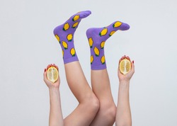 a female legs in colorful socks with lemons isolated on white background