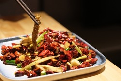 close up chopsticks picking up spicy pork aorta. Traditional Chinese Sichuan cuisine 