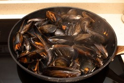 Cooking mussels in a pan. Mussels are perfect in endless fish recipes, but the simplest and most traditional in Galicia are steamed mussels.	