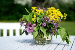 Bouquet of summer flowers freshly picked from the garden in a vase on a white wooden table outdoors in the garden