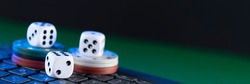 Online gaming platform, casino and gambling business. Casino dice and chips on laptop keyboard on green background.