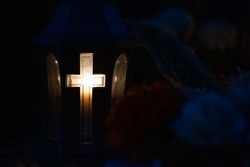 A candle with a cross burns in the evening at the cemetery