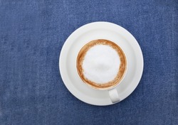 Cappuccino or latte with frothy foam, coffee cup top view on blue background. Cafe and bar, barista art concept.