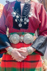 Vintage silver jewelry. Traditional women's clothing. A young woman in Bulgarian folk costume. Silver ornaments, red robe and silver belt. Female hands in Vintage silver jewelry