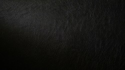 Macro shot of detailed black leather background. Dark textured close-up on quality leather parchment. Can be used in the background for luxury products and designs.