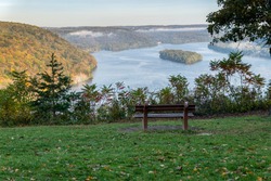 Bench over look misty Susquehanna river in the early autumn morning. With inland.