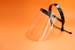 
Face protector on an orange background. Face shield used to protect against coronavirus. transparent face protector.