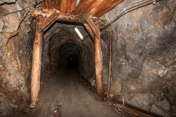 Old abandoned gold mine underground tunnel with wooden timbering