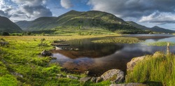 Large panorama with sunken paddle boats in Lough Gummeenduff. Beautiful Black Valley at sunset, MacGillycuddys Reeks mountains, Ring of Kerry, Ireland