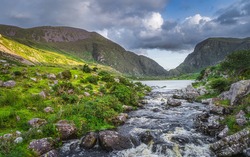 Beautiful landscape with mountain river flowing from Black Lake in Gap of Dunloe. Green hills at sunset in Black Valley, MacGillycuddys Reeks mountains, Ring of Kerry, Ireland
