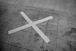 Black and white photo of a street parking spot marked with a large X sign