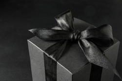 Black gift box with bow on black background, close up