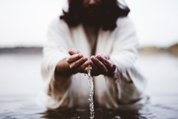 A closeup shot of Jesus Christ holding water with his palms