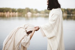 A shallow focus shot of a female grabbing the hand of Jesus Christ for healing and help