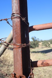 a vertical closeup of rusted gate fence post at a horse ranch in Amador County, California