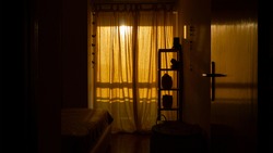 A vertical shot of a cozy room with a retro design and closed windows at the sunset time