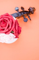 A vertical shot of roses and theb pegbox of a violin on orange background with a copy space