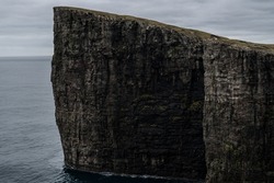 Cliffs of Faroe Islands  Blue ocean below the cliffs  Towering black cliffs on the coast of Faroe Islands