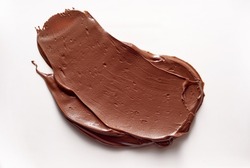 A closeup view of delicious chocolate paste smeared on white background in studio