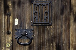 A closeup shot of an old door with a metal knocker and gri