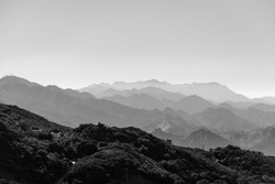 A monochrome shot of foggy mountain range layers, horizontal background