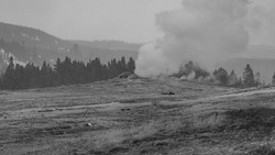 A greyscale shot of a field with the other side burning