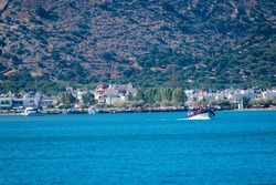 A blue waterscape with a boat floating in the background of a hilly coast, Crete island, Greece