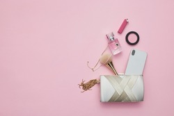 The content of a female purse on a pink background
