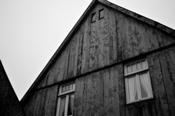 A greyscale shot of an old wooden house with a triangular roof