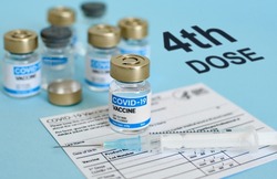 Close-up image of vaccine vial and syringe on CDC covid-19 vaccination record card  Fourth or 4th dose text on blue background 