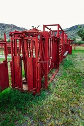 A closeup of Red colored Cattle squeeze chute on farm in Texas