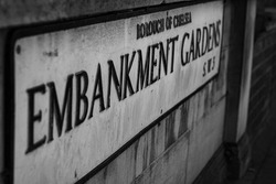 A grayscale shot of the Embankment gardens sign on the building wall