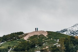 A beautiful view of two people standing on top of a hill surrounded by mountains in Slovenia
