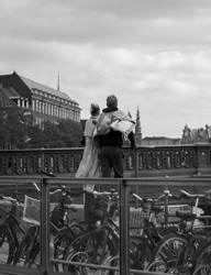 A vertical grayscale shot of a couple standing on a bridge in Copenhagen, Denmark