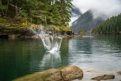A scenic view of a water splash in a lake in a forest