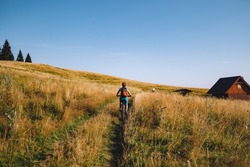 A woman biker riding through a meadow at goldenhour